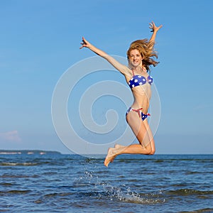 Cheerful girl jumping at sea