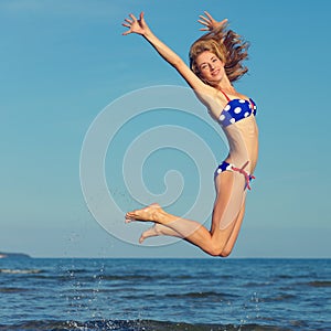 Cheerful girl jumping at sea