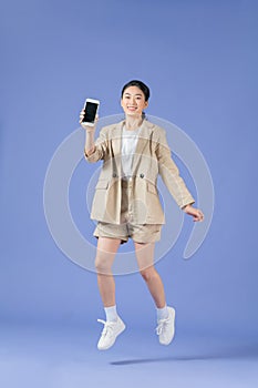 Cheerful girl jumping up and newest smartphone showing empty screen, enjoying new application for mobile phone