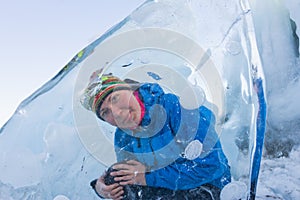 Cheerful girl looking through the transparent ice floe in Lake B