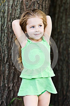 Cheerful girl posing at camera holding herself with arms