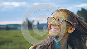 Cheerful girl posing smeared in multi-colored powder.