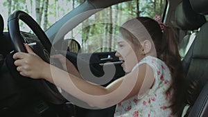 Cheerful girl pressing car horn on steering wheel