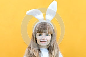 Cheerful girl with rabbit ears on her head on a yellow background. Funny crazy happy child. Easter child. Preparation for the