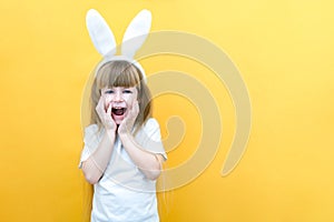 Cheerful girl with rabbit ears on her head on a yellow background. Funny crazy happy child. Easter child. Preparation for the