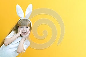 Cheerful girl with rabbit ears on her head on a yellow background. Funny crazy happy child. hands a rabbit. Preparation for the