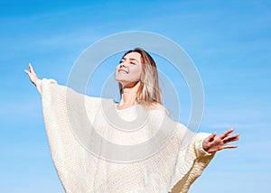 Cheerful girl with raised hands on the field in warm autumn season.