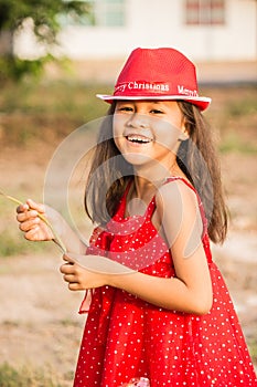 A cheerful girl in a red dress, wearing a Christmas hat and having fun taking pictures.