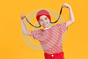 Cheerful girl in red outfit laughing merrily and holding on to her pigtails photo