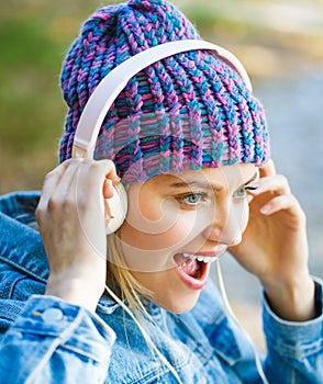 Cheerful girl rejoicing listening music in headphones smiling. Girl listens to music in headphones. Listening to music