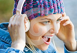 Cheerful girl rejoicing listening music in headphones smiling. Girl listens to music in headphones. Listening to music