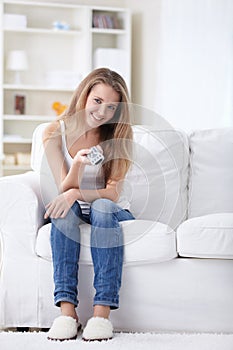 Cheerful girl with a remote control for TV