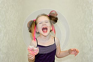 A cheerful girl screams after trying a pink donut.
