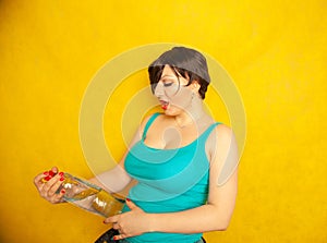 Cheerful girl with short hair with a big bottle of water on a yellow background in the Studio