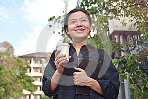 Cheerful  girl standing outdoor holding paper cup with coffee