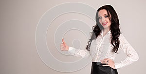 Girl student shows thumb up. Concept of education. Portrait, grey background, copy space