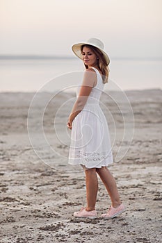 Cheerful girl at sunset in a white dress