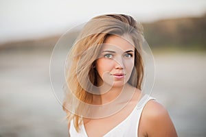 Cheerful girl at sunset in a white dress