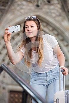 Cheerful girl is taking photo on her phone