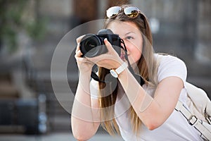 Cheerful girl is taking photos on her camera