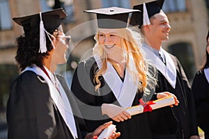 Cheerful girl talking to her groupmate during graduation.