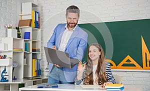 cheerful girl with teacher in classroom use laptop