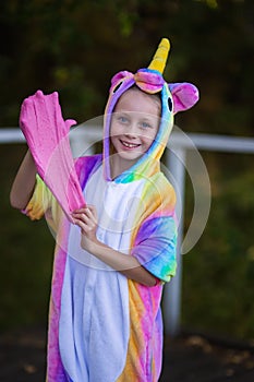Cheerful girl in a unicorn costume plays with a pink slime