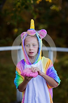 Cheerful girl in a unicorn costume plays with a pink slime