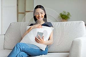 Cheerful Girl Using Cellphone Browsing Internet Sitting At Home