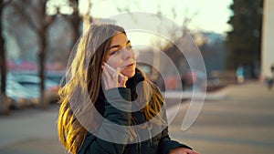 Cheerful girl using smartphone on street at sunset