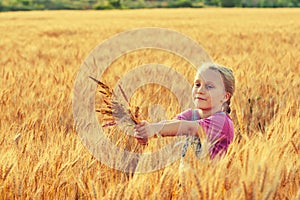 Cheerful girl on a walk near the field with wheat