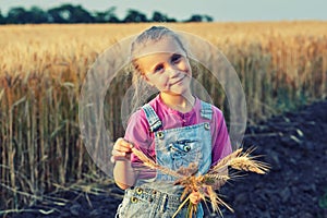 Cheerful girl on a walk near the field with wheat