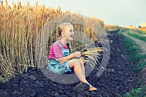 Cheerful girl on a walk near the field with wheat