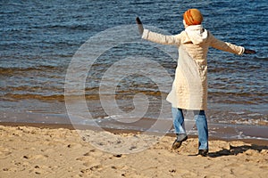 Cheerful girl walks on beach in solar autumn day