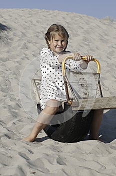 Cheerful girl on the wooden swing