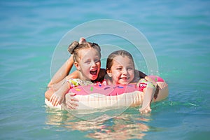 Cheerful girlfriends float on a circle on the sea