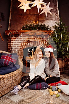cheerful girlfriends in the New Year's decorations in the fireplace