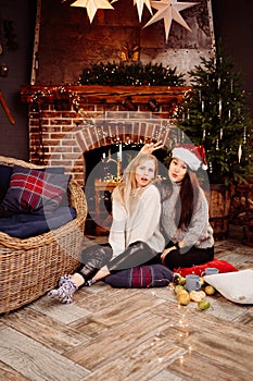 cheerful girlfriends in the New Year& x27;s decorations in the fireplace