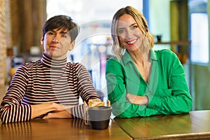 Cheerful girlfriends sitting at table in bar