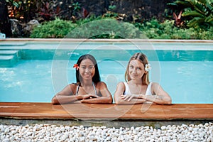 Cheerful girls in bikini swim in pool and enjoy journay in Thailand photo