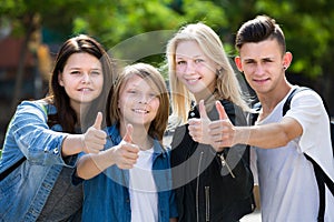 Cheerful girls and boys posing with thumbs up