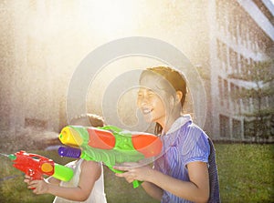 Cheerful girls playing water guns in the park