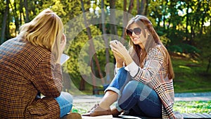 Cheerful girls sitting in park and browsing social media