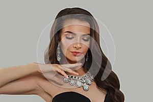 Cheerful glamorous woman jewelry model with diamonds posing on gray background