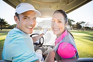 Cheerful golfer couple sitting in golf bugggy