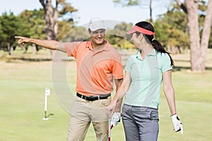 Cheerful golfer man pointing while standing by woman