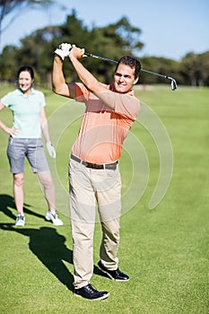 Cheerful golfer taking shot