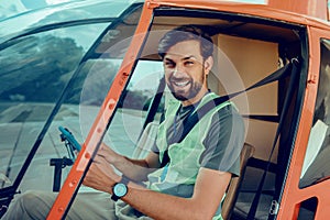 Cheerful good-looking man sitting on the front seat of the helicopter