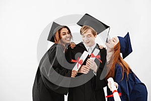 Cheerful graduate classmates celebrating smiling rejoicing over white background.