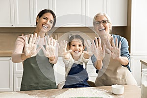 Cheerful grandmother, happy mother and girl showing floury hands